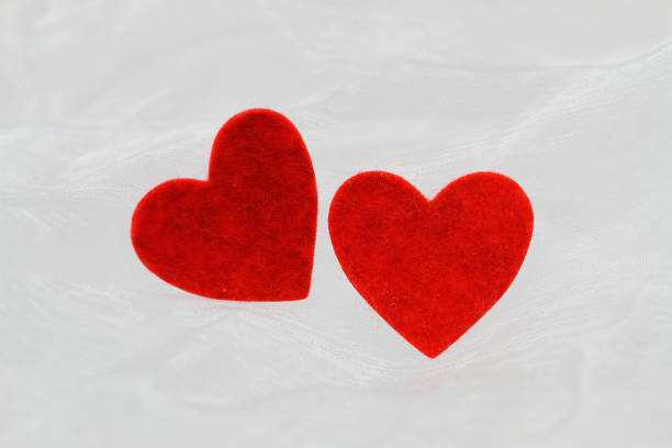 istock Two red hearts on white cloth with copy space 1033299036