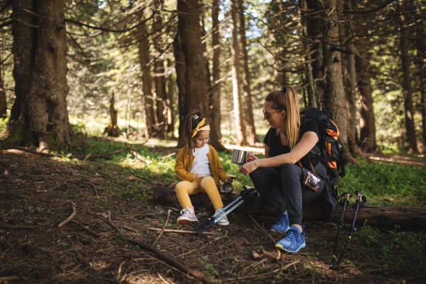 istock Mother and daughter relaxing in forest after a long hike 1033299420