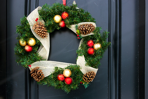 Close up of Christmas wreath outside on black door.
