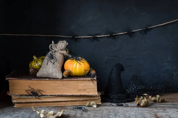 Halloween holiday background with pumpkin lantern spiders old books black witchhat toned