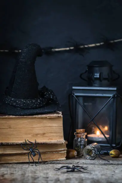 Halloween holiday background with lantern, spiders, old books, black witchhat, toned