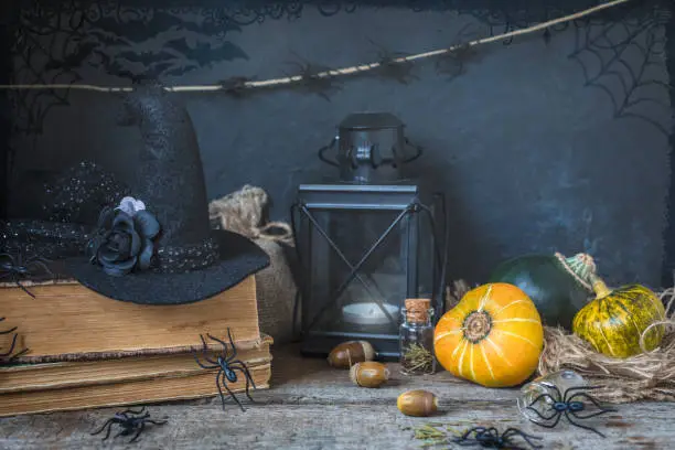 Halloween holiday background with pumpkin lantern spiders old books black witchhat toned