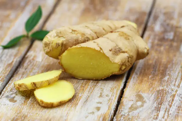 Photo of Slices of fresh ginger on rustic wooden surface