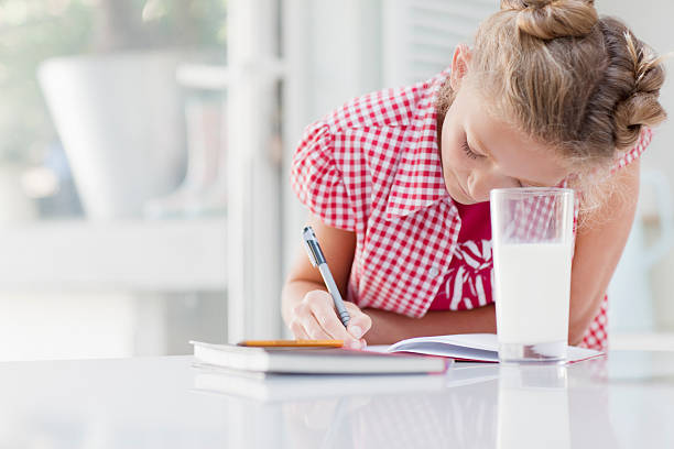 Girl doing homework with glass of milk  12 13 years pre adolescent child female blond hair stock pictures, royalty-free photos & images