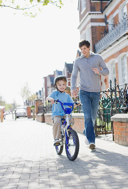 padre e figlio in esecuzione insieme all'aperto di bicicletta di equitazione - bicycle london england cycling safety foto e immagini stock