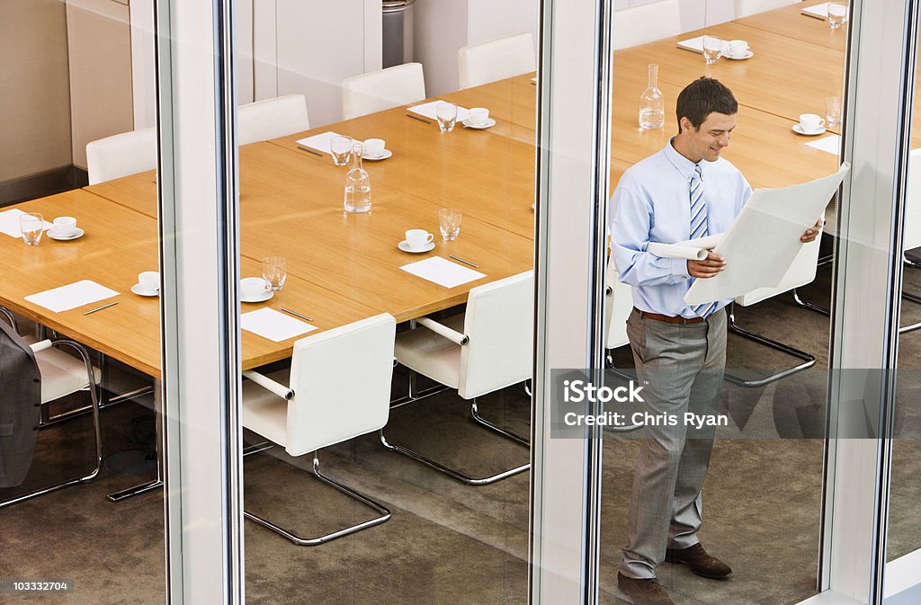 Uomo d'affari visualizzando cianografie in sala conferenze finestra - Foto stock royalty-free di 35-39 anni