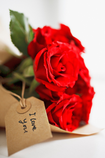 Composition for Valentine's Day with a gift box and a bouquet of roses on a blurred background with bokeh lights.
