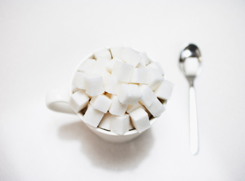 top view of white and brown sugar cubes scattered on dark wooden background with copy space