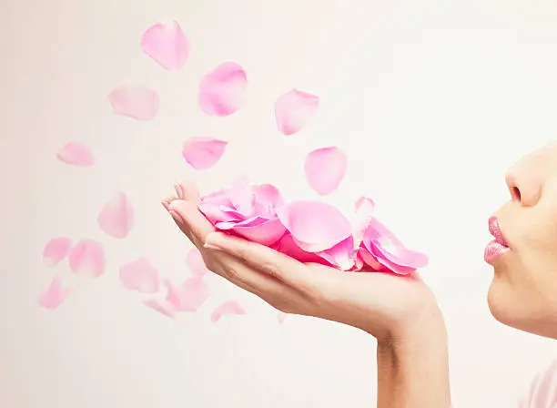 Photo of Woman blowing pink rose petals