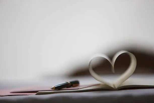 Photo of Pen and pages of notebook forming heart-shape
