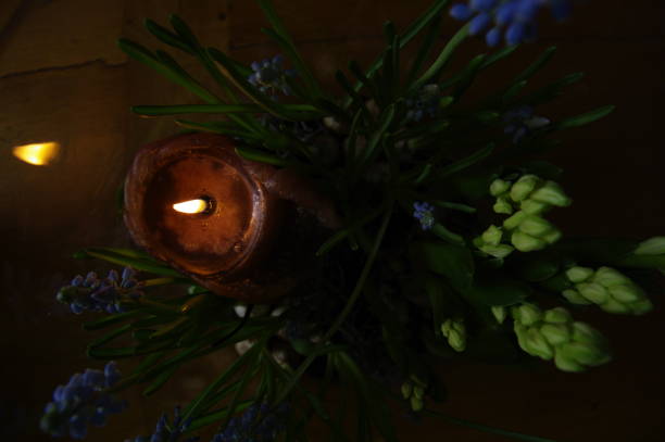 Candle with spring flowers in a vase as dcoration standing a a table