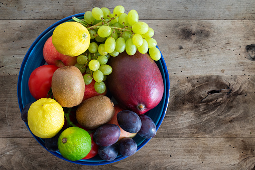 top view of bowl filled with fresh fruits on rustic wooden table