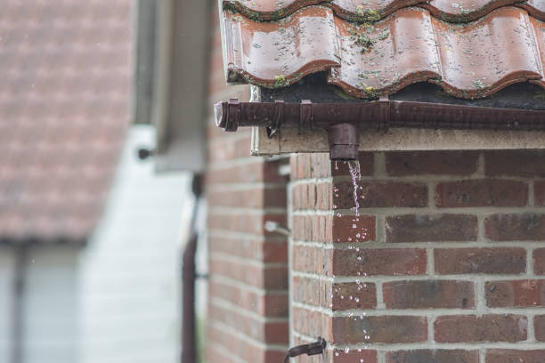 Broken gutter missing a downpipe. House guttering repair leaking water Broken gutter missing a downpipe. House guttering repair leaking rain water. Drainage problem with brown UPVC pipe. ian stock pictures, royalty-free photos & images