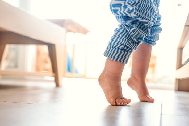 Baby boy Photo of Baby legs. First steps. Close up of baby feet doing the first steps at home, learning to walk. Barefoot stock pictures, royalty-free photos & images