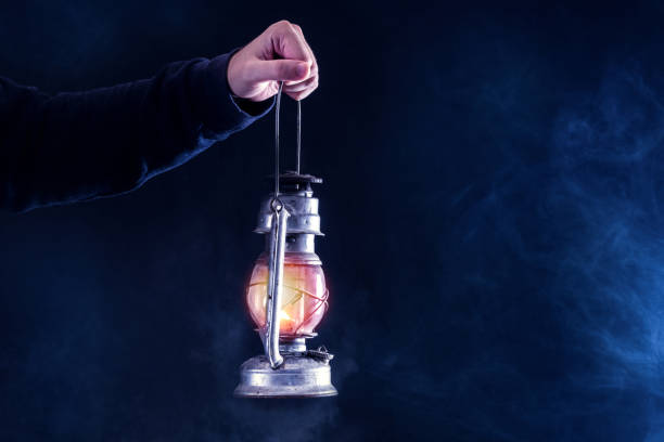 man hand holding gas lamp on dark and night smoked foggy background - oil lantern imagens e fotografias de stock