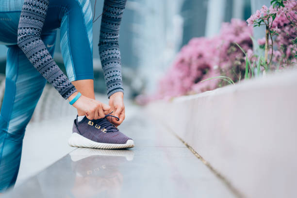 Tying shoelaces Runner tying her shoelaces bound woman stock pictures, royalty-free photos & images