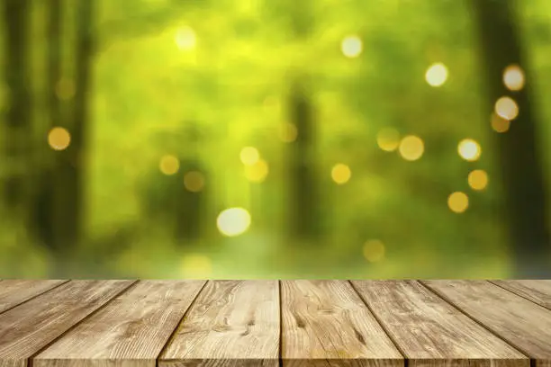 Old wooden table with blurred summer forest bokeh background.