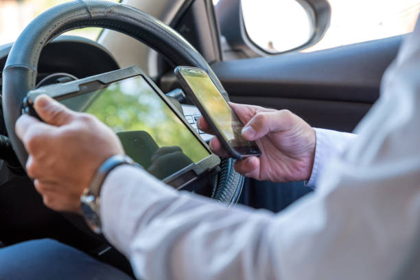 istock Businessman working on tablet and smartphone inside car on bright day 1033395056
