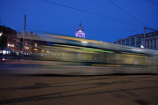 A tram passing by the Old Market Square of Nottingham city at night. The Exxhange building in the background. Long exposure.