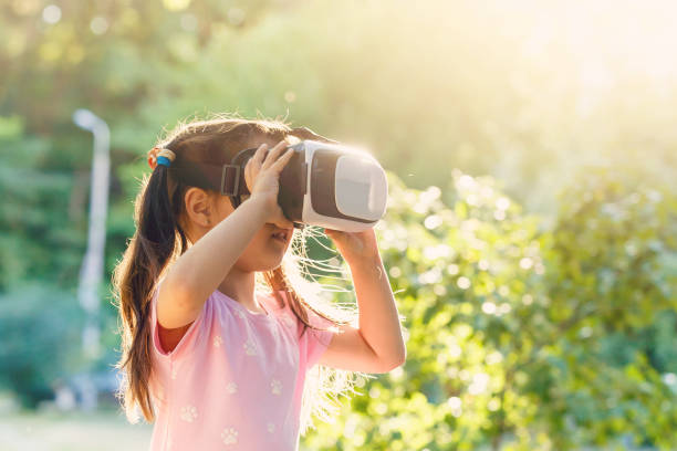 istock Child with virtual reality headset sitting behind natrue outdoors at home. 1033401864