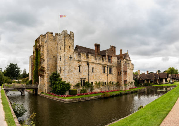 HEVER CASTLE, ENGLAND, UK – SEPTEMBER 08 2018: View of Hever Castle and its moat HEVER CASTLE, ENGLAND, UK – SEPTEMBER 08 2018: View of Hever Castle and its moat on a cloudy day, with a flag flying at full mast. Hever Castle stock pictures, royalty-free photos & images