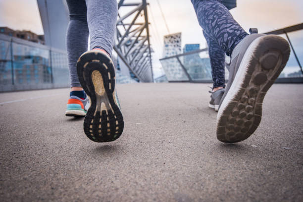 istock Unknown athlete couple jogging on dock at sunset, close up. 1033437280