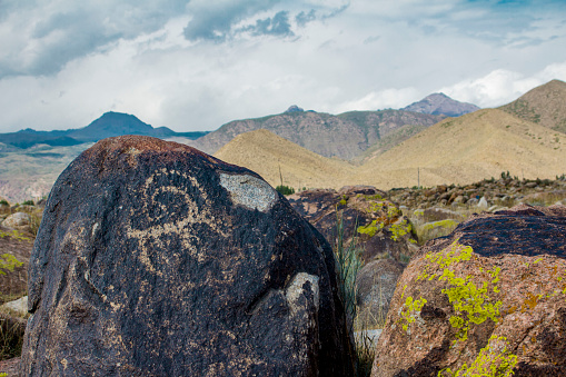 real petroglyphs on natural stone found in the steppe, on a blurred background of beautiful mountains