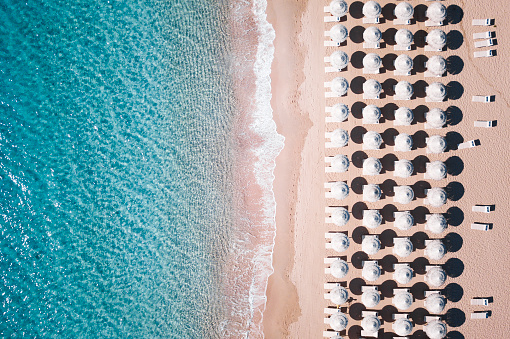 Aerial view of  white umbrellas and sun loungers. Beautiful sunny summer day in Sardinia,Mediterranean sea, Italy.