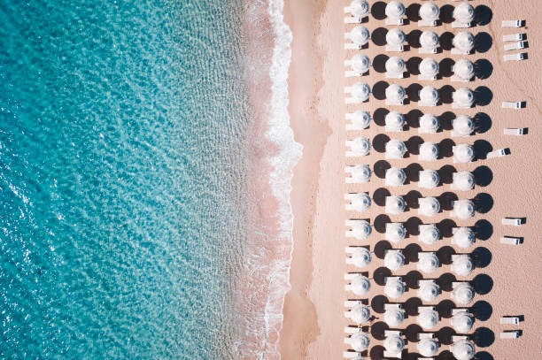 Aerial view of  white umbrellas and sun loungers. Beautiful sunny summer day in Sardinia,Mediterranean sea, Italy. Aerial view of  white umbrellas and sun loungers. Beautiful sunny summer day in Sardinia,Mediterranean sea, Italy. beach umbrella aerial stock pictures, royalty-free photos & images
