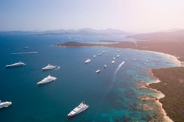 view from above, aerial picture of the amazing emerald coast with a turquoise and transparent mediterranean sea full of luxury yachts and boats during the summer season, sardinia, italy. - inflatable raft nautical vessel sea inflatable imagens e fotografias de stock