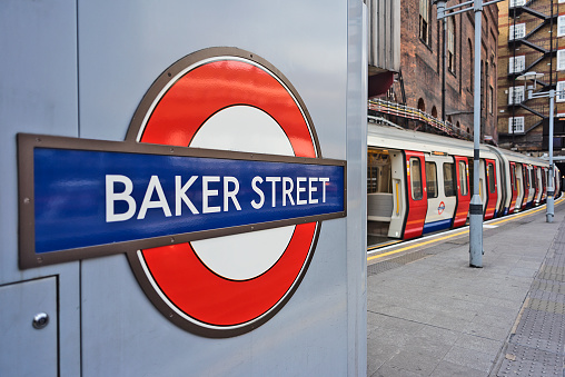 Baker Street underground station logo sign, on the background the platform and the Metropolitan line train.