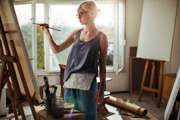 istock Young woman painting on canvas 1033496848