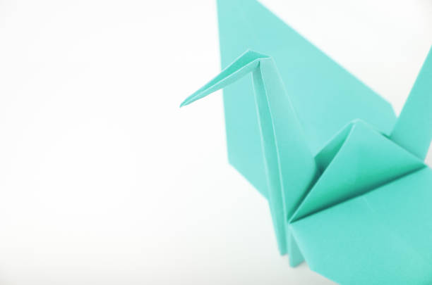 Blue origami crane; bird isolated closeup on white background.