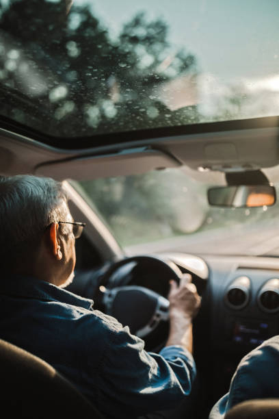 experienced older man with glasses drives a car - old men car vertical imagens e fotografias de stock