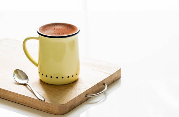 istock Yellow cup of coffee on wooden plate on white table 1033510640