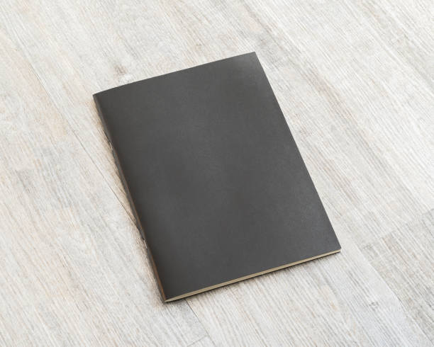 istock Mockup book with blank black leather cover template paper texture on wood table 1033516152
