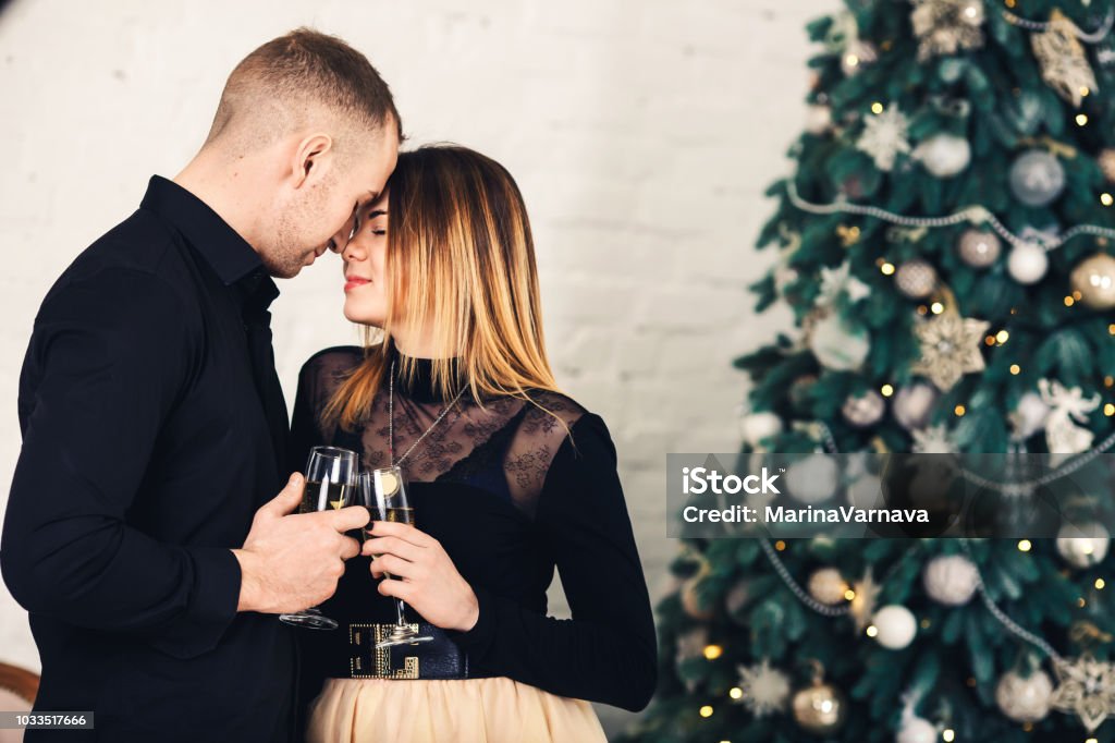 Pareja Amorosa En Ropa Elegante Con Copas De Vino En Navidad Foto de stock  y más banco de imágenes de Abrazar - iStock
