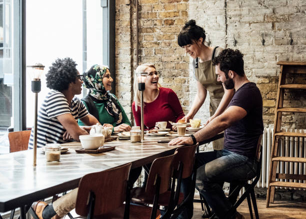 istock Waitress putting down food and drink on table and customers laughing 1033525854