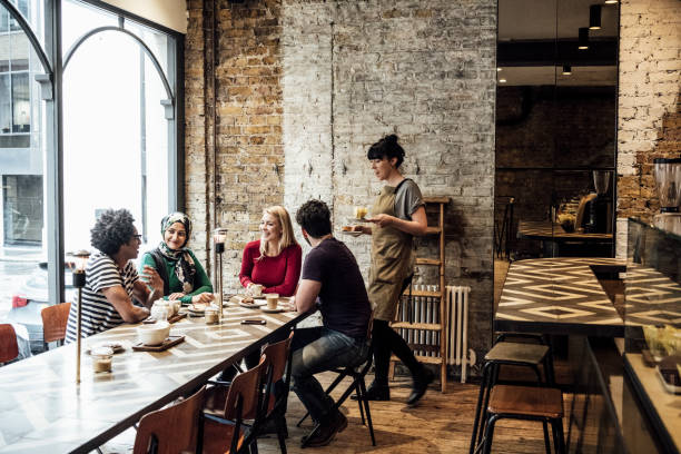 istock Group of friends in cafe being served drinks by waitress 1033525868
