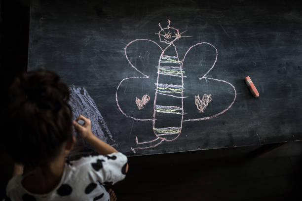 Child friends drawing on floor using chalk outdoors