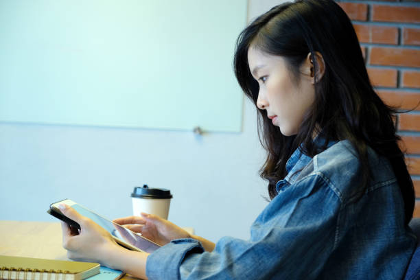 istock Young asian woman using tablet while sitting in  room background, people and technology, lifestyle, adult online education, working from home 1033542922