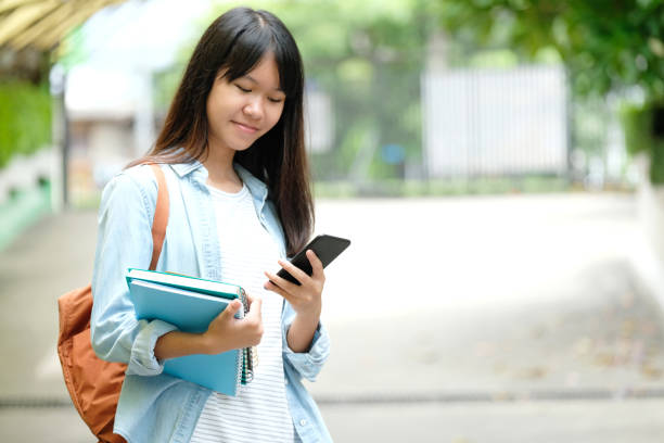 istock Student girl holding books and using smartphone, online education, technology communication 1033552772