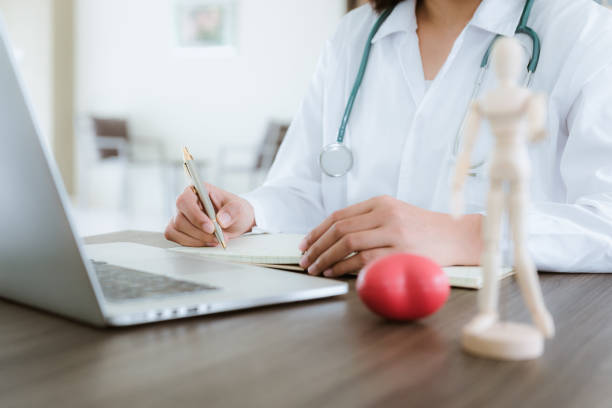 istock Close up portrait of female doctor is taking note while looking at laptop computer 1033564146