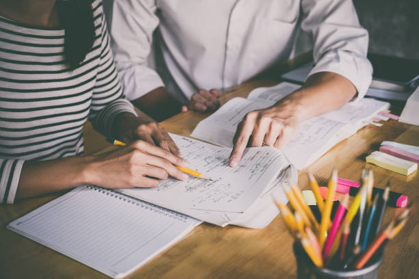 istock High school or college student group catching up workbook and learning tutoring in classroom and reading, doing homework and lesson practice preparing exam 1033601018