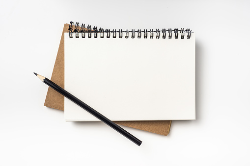 Blank white notebook and pen on wooden table