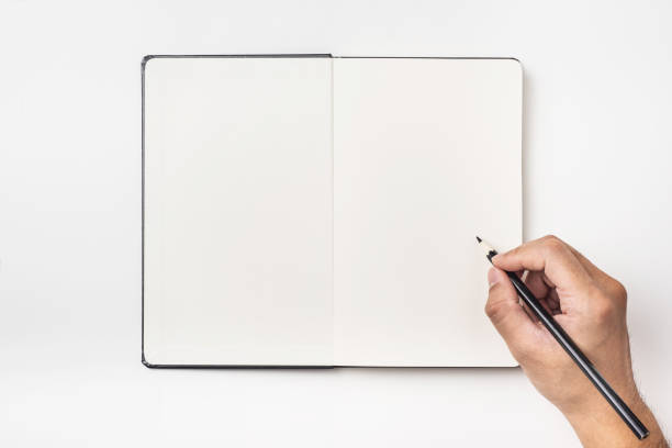 istock man's hand hold black pencil above black hardcover notebook 1033615646