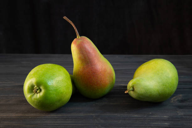 istock green ripe pear on black wooden background 1033633690