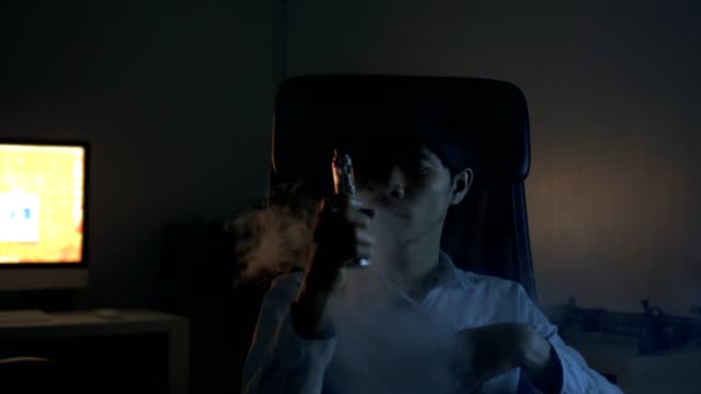 young man sitting on chair smoking electronics cigarette