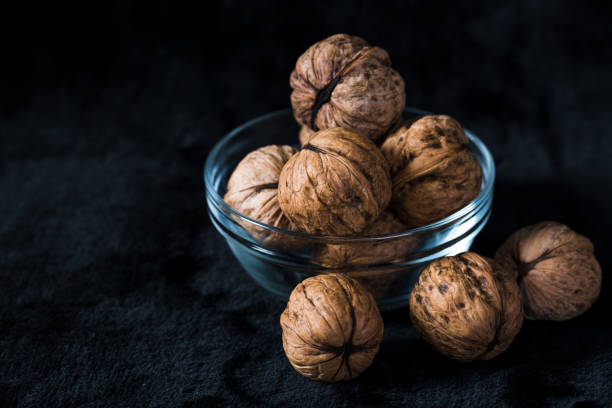 istock Walnuts in glass bowl on black 1033654426