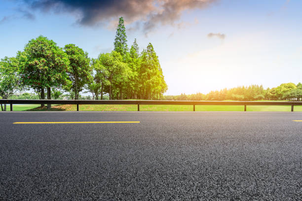 istock Empty asphalt road and green woods at sunset 1033654484